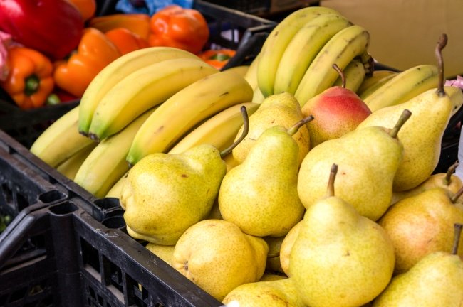 Frutas e verduras , peras, bananas e pimentões vermelhos em uma cesta de feira