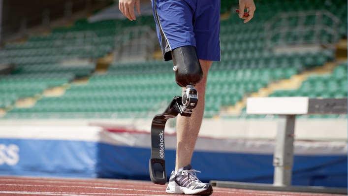 Homem usando próteses esportivas caminhando em pista de corrida